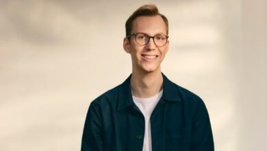 Portrait of a smiling man with glasses against a neutral background.