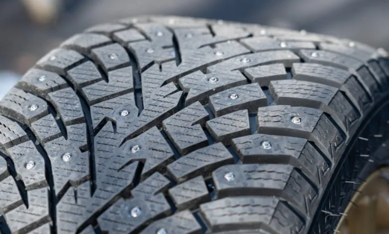 Close-up of a studded winter tire with aggressive tread pattern.