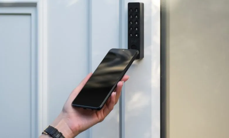Person unlocks door with NFC keypad and smartphone.