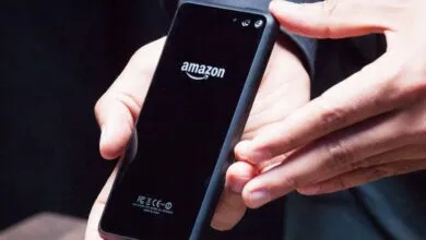 Hands holding a black smartphone with the Amazon logo on the back.