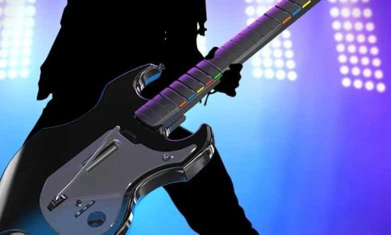 Guitar Hero-style controller with colorful fret buttons and stage lighting.