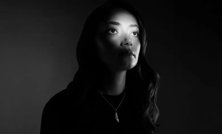 Black and white portrait of a woman looking upwards with dramatic lighting.