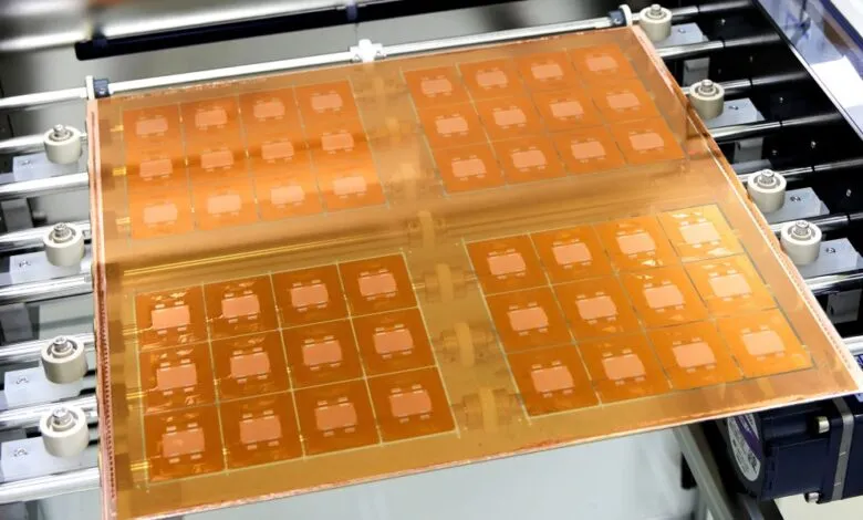 Large copper-colored panel with multiple integrated circuits being processed by a machine.