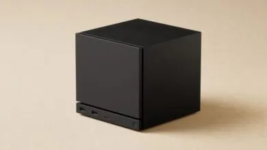 Black cube-shaped device with ports on a beige surface.