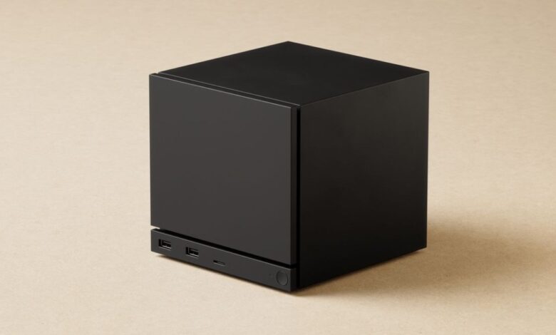Black cube-shaped device with ports on a beige surface.