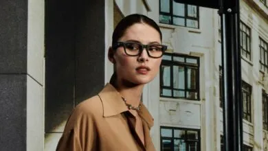 Woman wearing matte black rectangular eyeglasses and a tan shirt.