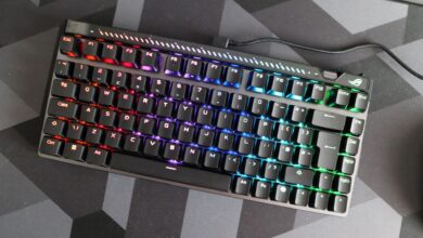 ROG Strix Scope NX TKL keyboard with vibrant RGB lighting on a dark geometric mat.