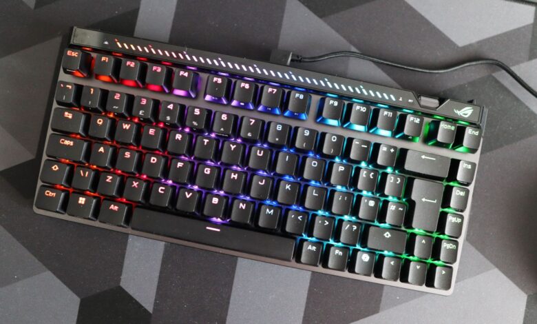 ROG Strix Scope NX TKL keyboard with vibrant RGB lighting on a dark geometric mat.