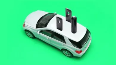 White toy car with electrical plug on top against a green background.