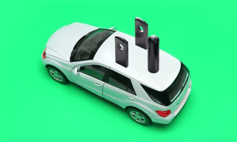 White toy car with electrical plug on top against a green background.