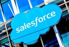 Salesforce logo on a modern glass building, blue cloud with white text.