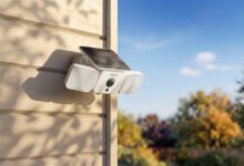 White Reolink security camera with solar panel mounted on a beige wall.