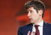 Man in suit speaking with animated expression, looking off-camera.