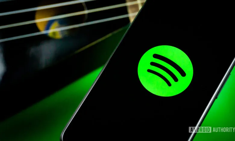 Spotify logo displayed on a smartphone screen with guitar strings in background.