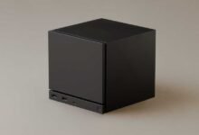 Black cube-shaped computer with USB ports on a neutral background.