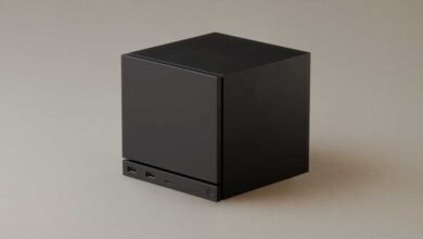 Black cube-shaped computer with USB ports on a neutral background.