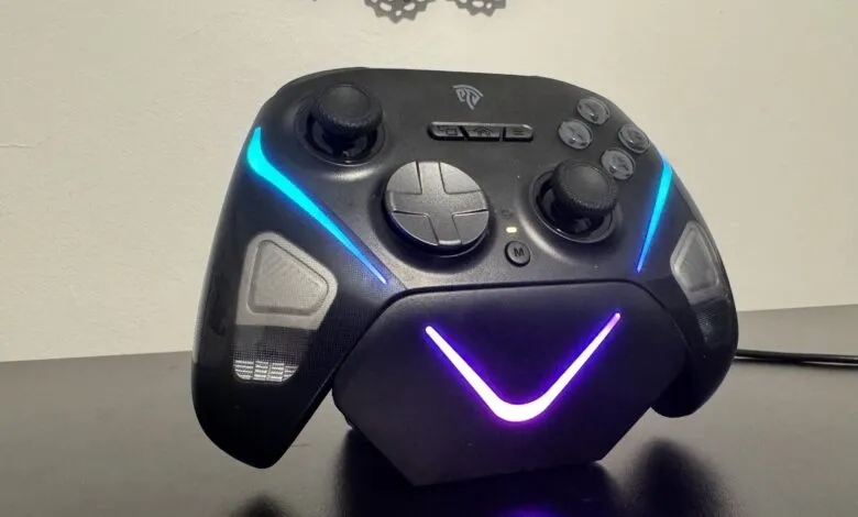 Black gaming controller with blue and purple LED lights on charging dock.