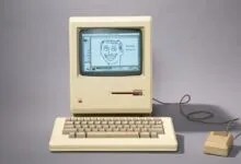 Vintage Macintosh computer with a drawing of a face on the screen.