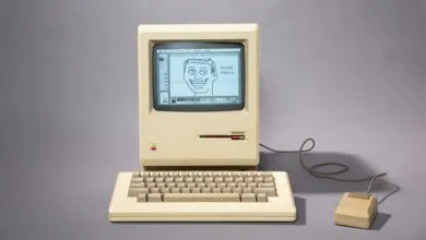 Vintage Macintosh computer with a drawing of a face on the screen.