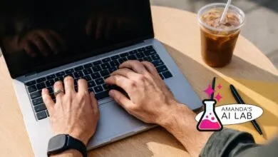 Hands typing on laptop with coffee, notebook, and pen on a wooden table.