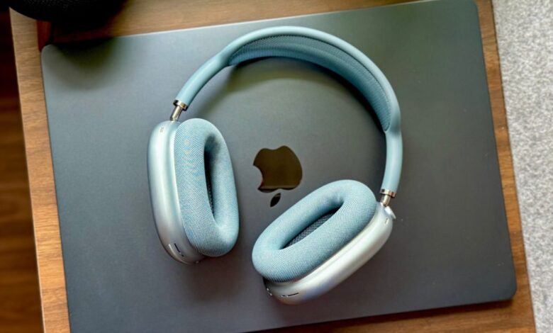 Sky blue AirPods Max headphones resting on a closed gray Apple laptop.