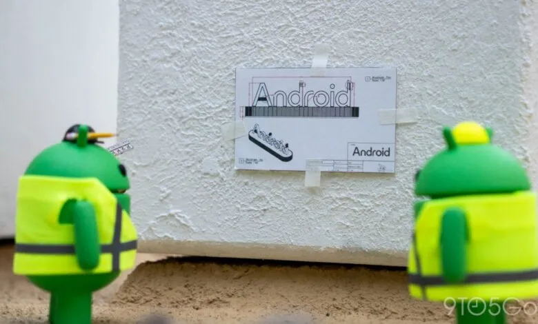 Two Android figures inspect a blueprint of the Android logo.