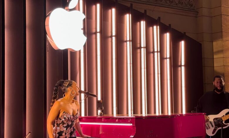 Alicia Keys performs on stage with a pink piano and Apple logo backdrop.