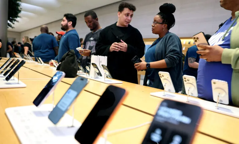 People browse iPhones on display at a busy Apple store.