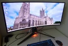Curved gaming monitor displays cathedral image, keyboard and mouse visible.