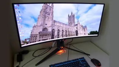 Curved gaming monitor displays cathedral image, keyboard and mouse visible.