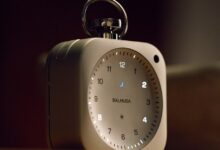 Balmuda alarm clock with illuminated numbers and a silver handle.