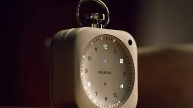 Balmuda alarm clock with illuminated numbers and a silver handle.