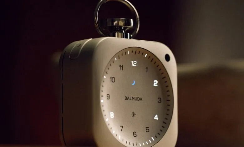 Balmuda alarm clock with illuminated numbers and a silver handle.
