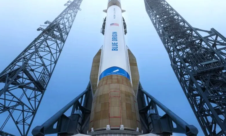 Blue Origin's New Glenn rocket stands tall on the launchpad, framed by support towers.