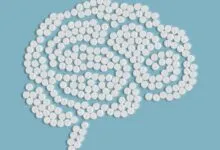 Brain shape formed by white pills on a light blue background.