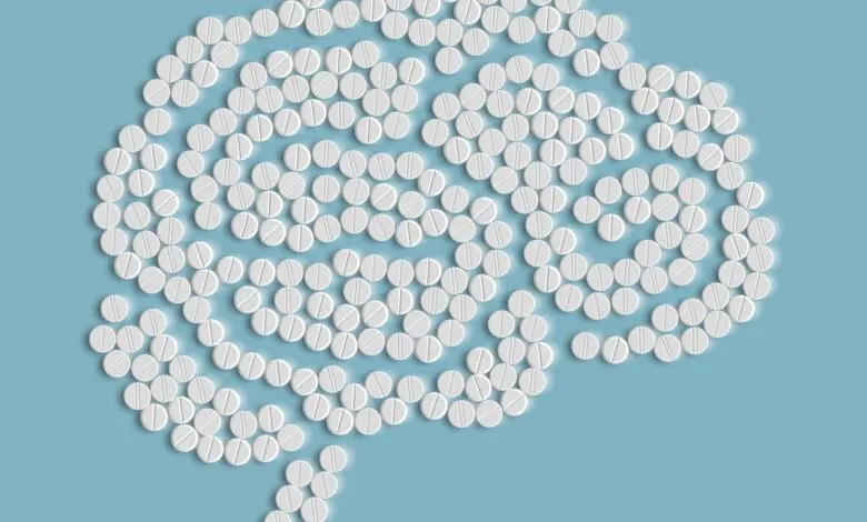 Brain shape formed by white pills on a light blue background.