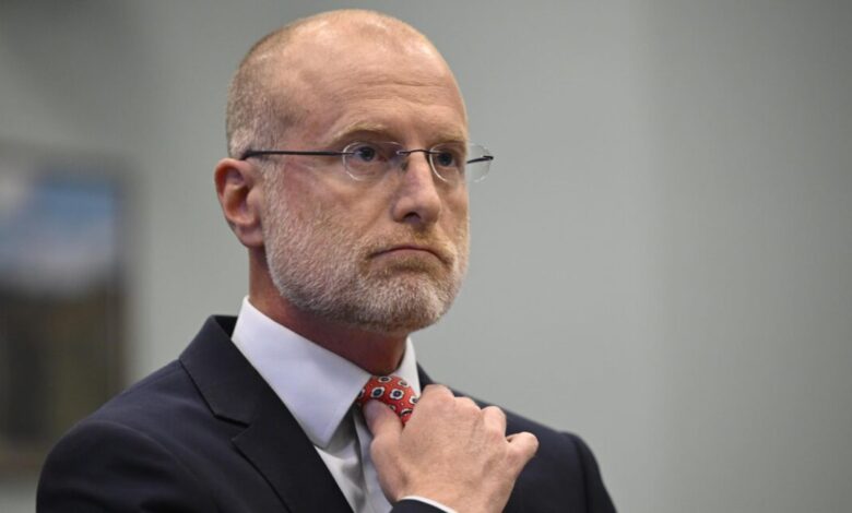 FCC Chairman Brendan Carr adjusts his tie during a hearing.