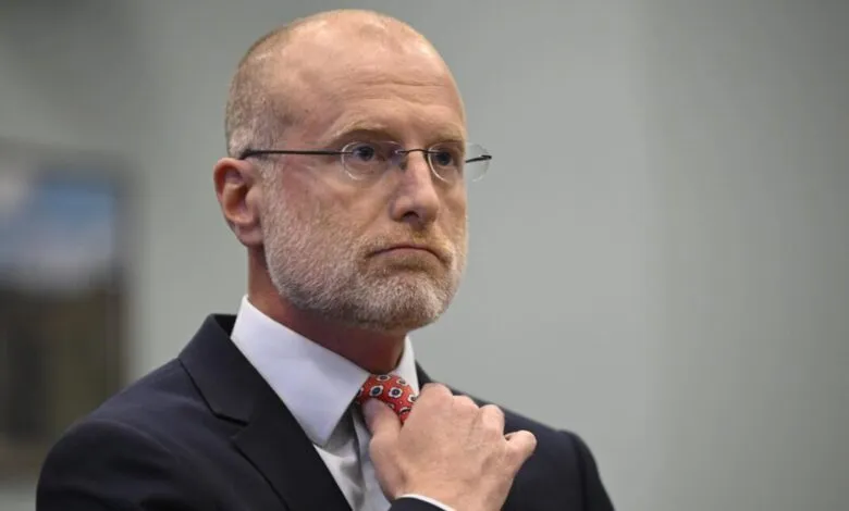 FCC Chairman Brendan Carr adjusts his tie during a hearing.