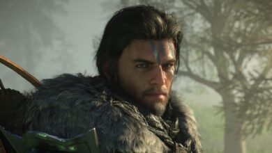 Man with blue face paint and fur collar stares intently.