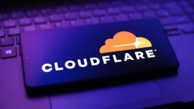 Smartphone displays Cloudflare logo on a laptop keyboard.
