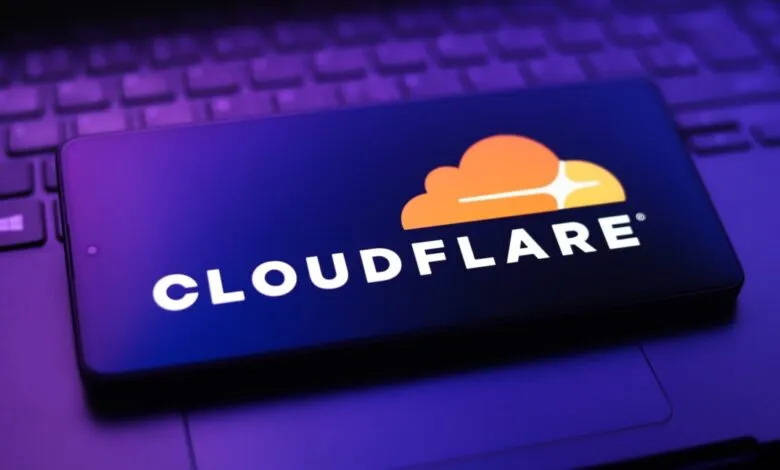Smartphone displays Cloudflare logo on a laptop keyboard.