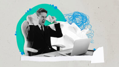 Frustrated man in suit tears paper at desk with laptop.