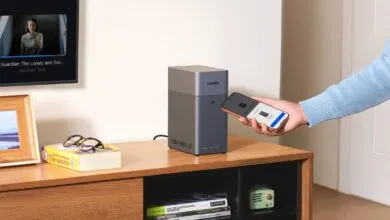 UGREEN NAS device being set up with a smartphone on a wooden cabinet.