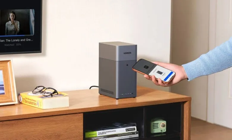 UGREEN NAS device being set up with a smartphone on a wooden cabinet.