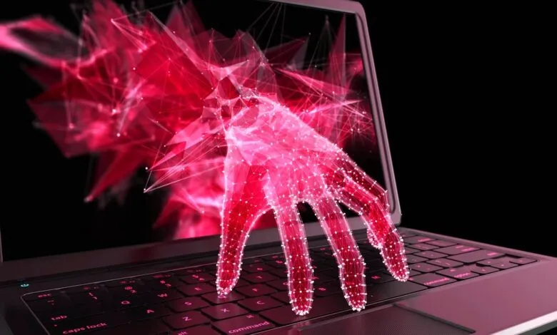 Abstract red hand emerging from laptop screen, touching keyboard.