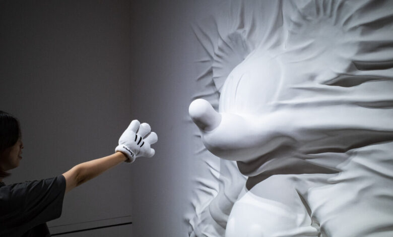 Person with Mickey Mouse glove reaching for a draped Mickey Mouse sculpture.