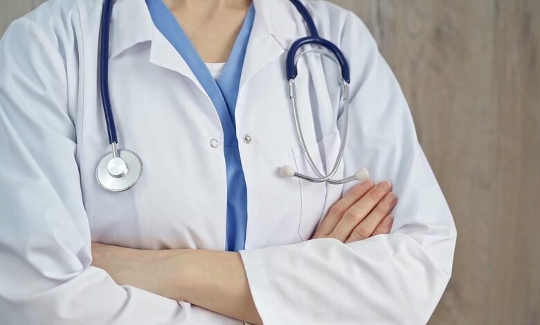 Doctor in white coat with stethoscope, arms crossed.