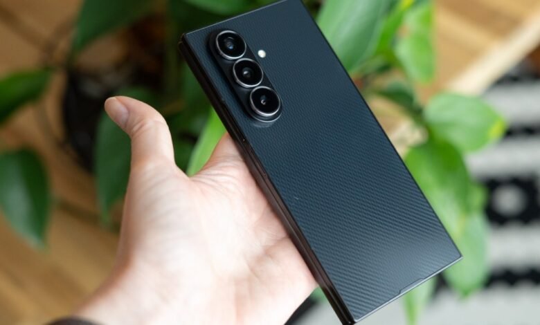 Hand holds a sleek, dark smartphone with a triple-lens camera system.