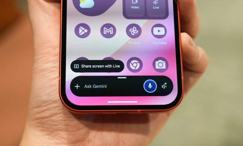 Close-up of a hand holding a smartphone displaying the Android home screen.