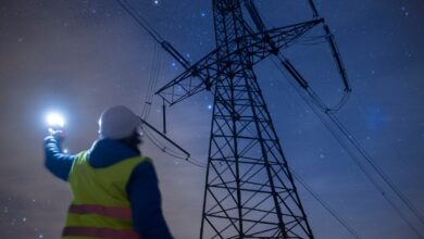 Electrical worker inspects power lines at night with flashlight.